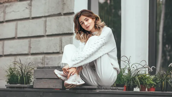 Beautiful young model girl happy and fashionable is sitting on a wooden terrace
