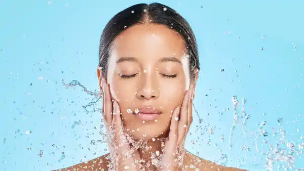 Shot of a beautiful young woman being splashed with water against a blue background