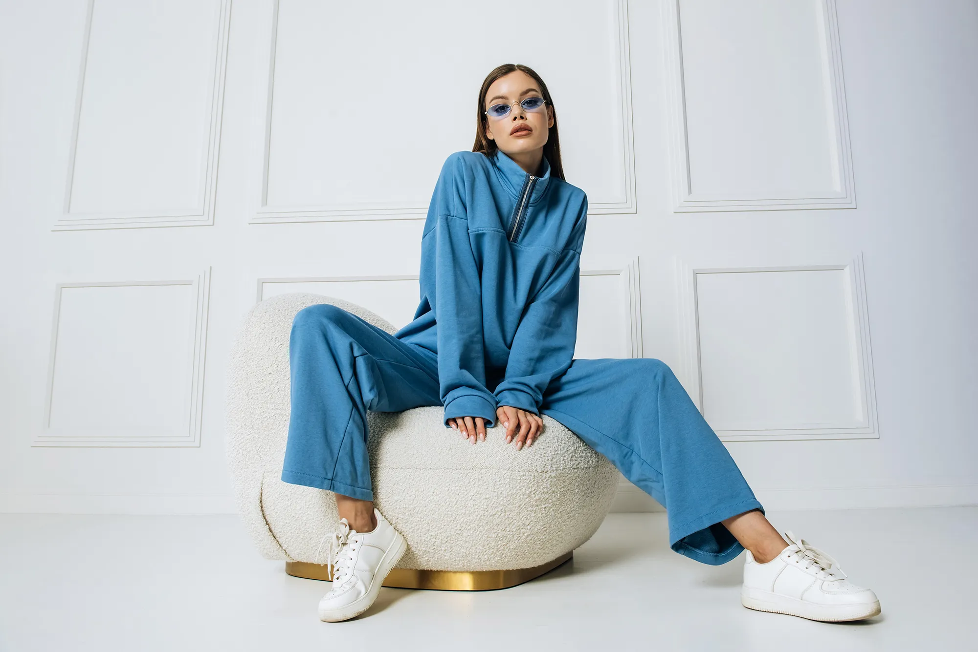 Beautiful fashion model posing sitting on armchair looking at camera indoors studio shot