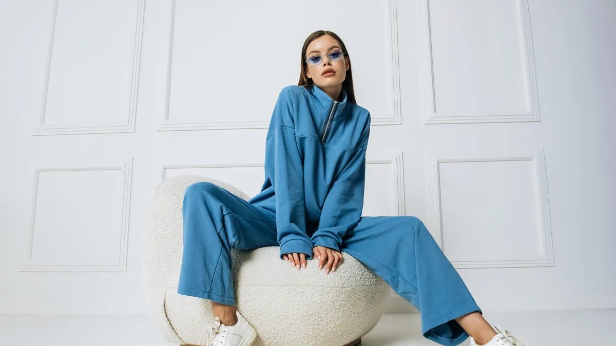 Beautiful fashion model posing sitting on armchair looking at camera indoors studio shot