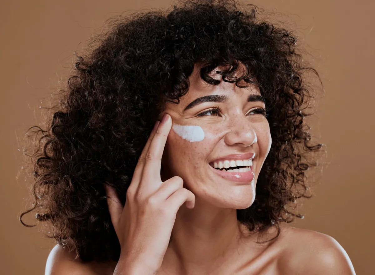 Woman putting sunscreen on face