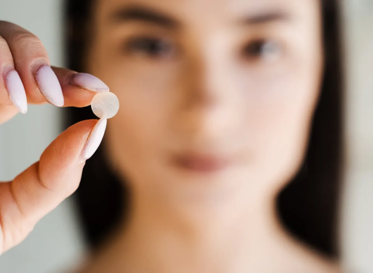 Woman holding a pimple patch