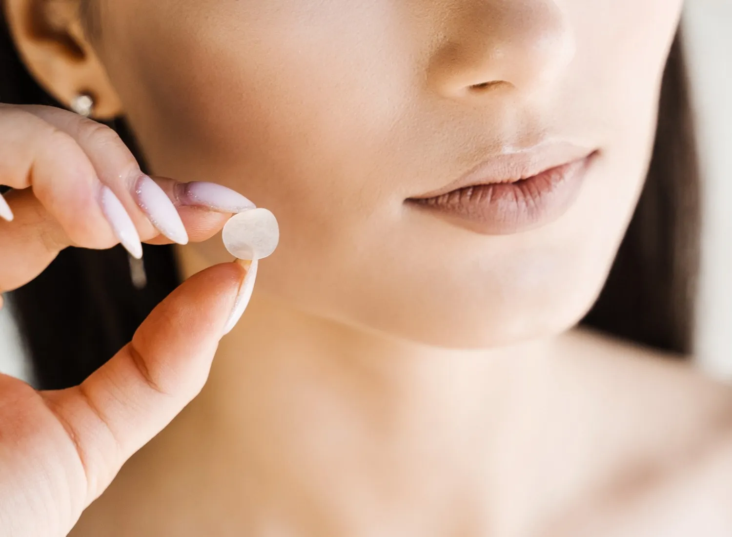 Woman holing a pimple patch up to her face