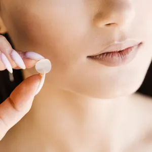 Woman holing a pimple patch up to her face