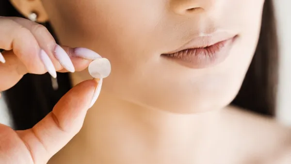 Woman holing a pimple patch up to her face