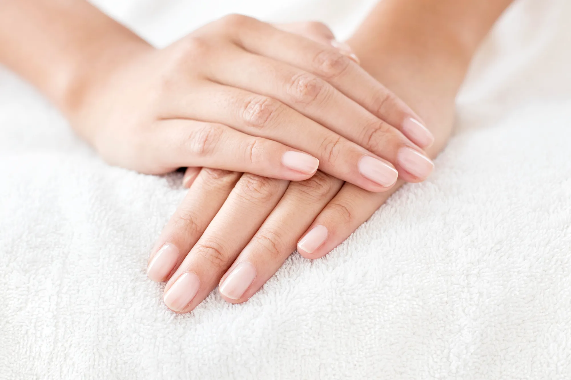 Young woman with hands resting on white towel.