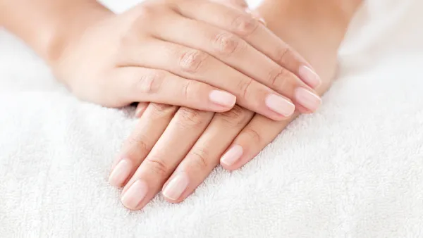 Young woman with hands resting on white towel.