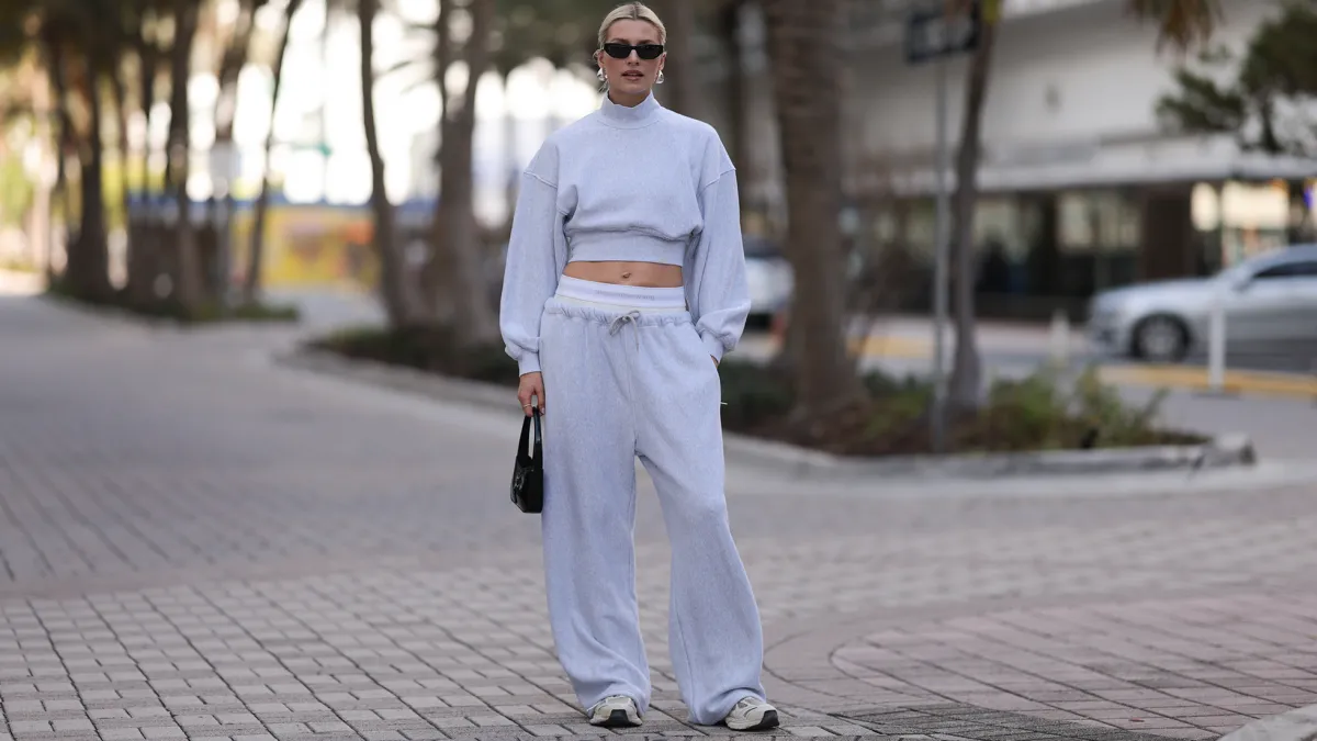 MIAMI, FLORIDA - DECEMBER 08: Lena Gercke seen wearing Saint Laurent black sunglasses, silver statement necklace, Alexander Wang light grey high neck cotton cropped jumper / sweater, Alexander Wang light grey cotton wide leg jogger pants with underwear detail, Saint Laurent black varnishes leather mini bag and Axel Arigato white leather sneakers, on December 08, 2023 in Miami, Florida. (Photo by Jeremy Moeller/Getty Images)2