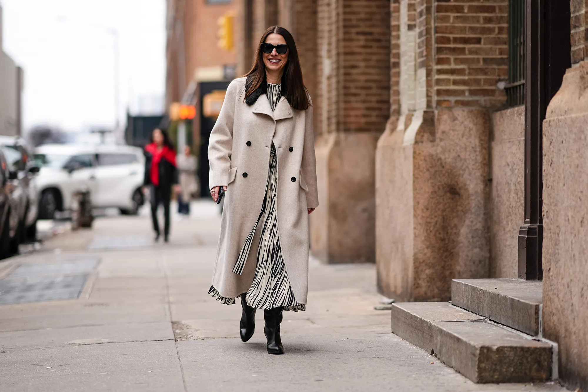 A guest wears sunglasses, a beige long fabric coat , a black and white striped / zebra print long dress, black leather boots, outside Proenza Schouler , during New York Fashion Week, on February 10, 2024 in New York City. (Photo by Edward Berthelot/Getty Images)