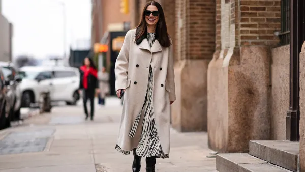 A guest wears sunglasses, a beige long fabric coat , a black and white striped / zebra print long dress, black leather boots, outside Proenza Schouler , during New York Fashion Week, on February 10, 2024 in New York City. (Photo by Edward Berthelot/Getty Images)