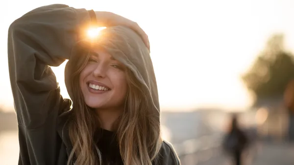 Playful teen woman outdoors in hooded sweatshirt