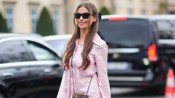 A guest wears sunglasses, a pink Chanel pajama with flared pants and printed polka dots, a Chanel bag, platform shoes, outside Chanel, during the Womenswear Fall/Winter 2024/2025 as part of Paris Fashion Week on March 05, 2024 in Paris, France.