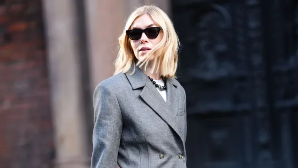 A guest wears sunglasses, a gray oversized blazer jacket , suit flared pants , shiny sequined shoes, a black woven leather Bottega Veneta bag, outside Herskind, during the Copenhagen Fashion Week FW24 on January 31, 2024 in Copenhagen, Denmark.