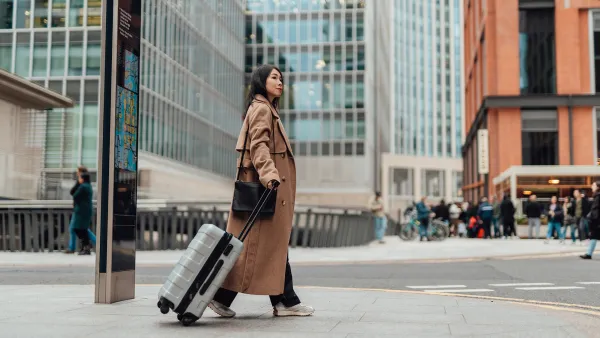 Young businesswoman carrying luggage, walking on the high street in the city.