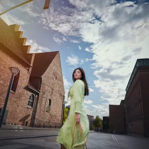 Model outdoors in city / street. Woman in green dress walking