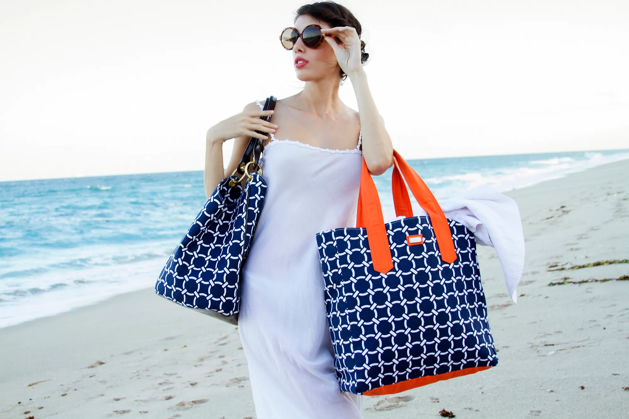 Beautiful woman on beach with sunglasses and fashionable bags on beach