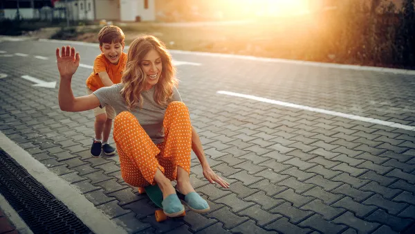 Mother and son playing in public park, driving skateboard
