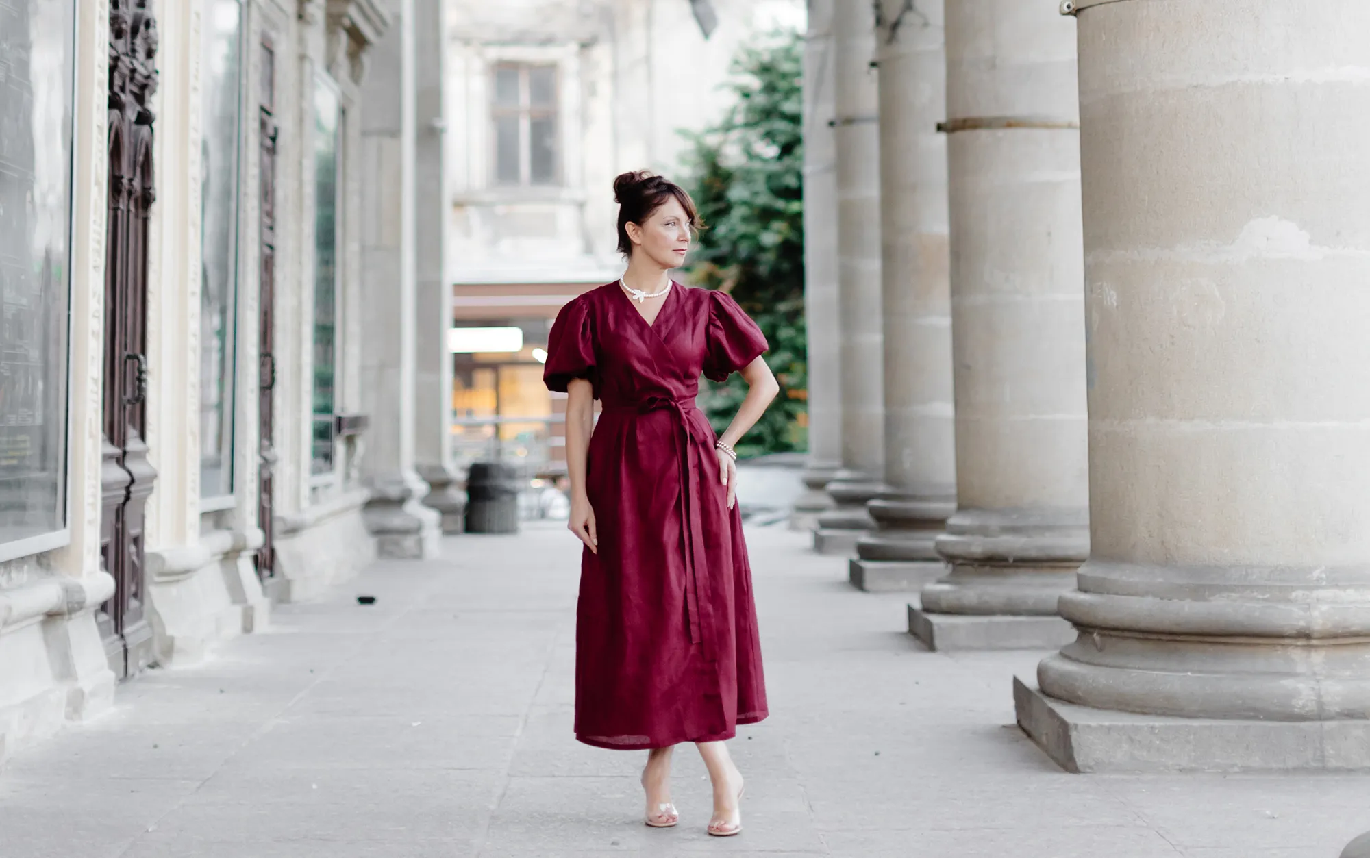 Woman in red dress is walking on street on old building background.