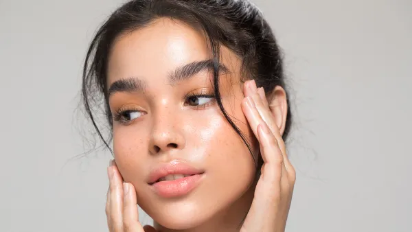 Close up studio shot of a beautiful young woman with perfect glow skin.