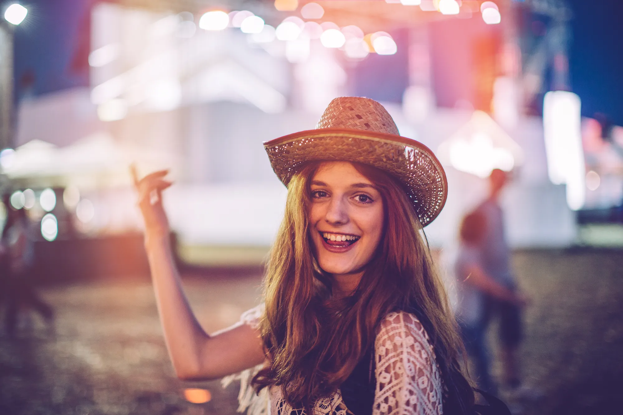 Young woman at summer festival. Dancing with her arms raised. Summertime.