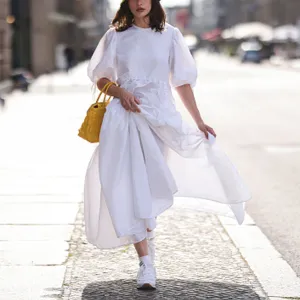 Woman wearing white dress and sneakers