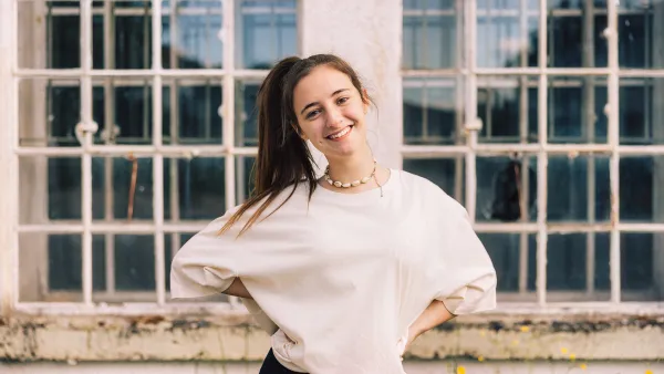 Young fashionable woman with ponytail wearing property released handmade craft designer T-Shirt Standing looking towards the Camera. Majestic industrial Window in the background. Millennial Generation Girl Young Fashion Design Portrait.