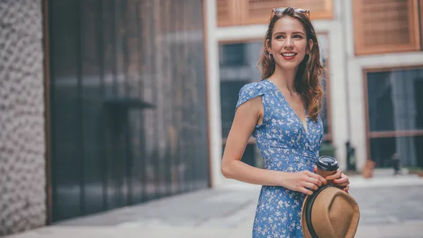 One woman, cute young woman in city, holding a coffee cup.