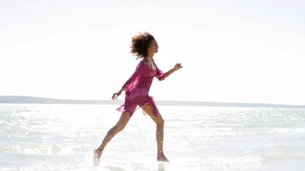 Woman in bikini and cover-up running in ocean