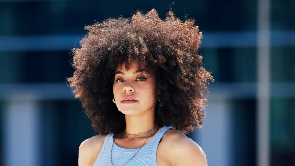 Portrait, fashion and attitude with a black woman in the city, outdoor on a bridge during a summer day. Street, style or urban and an attractive young female posing outside with an afro hairstyle