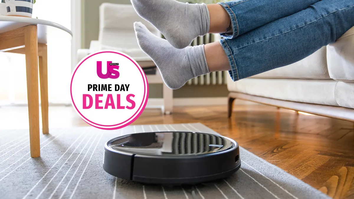 Young woman lift up the feet for letting robotic vacuum cleaner pass though