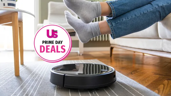Young woman lift up the feet for letting robotic vacuum cleaner pass though