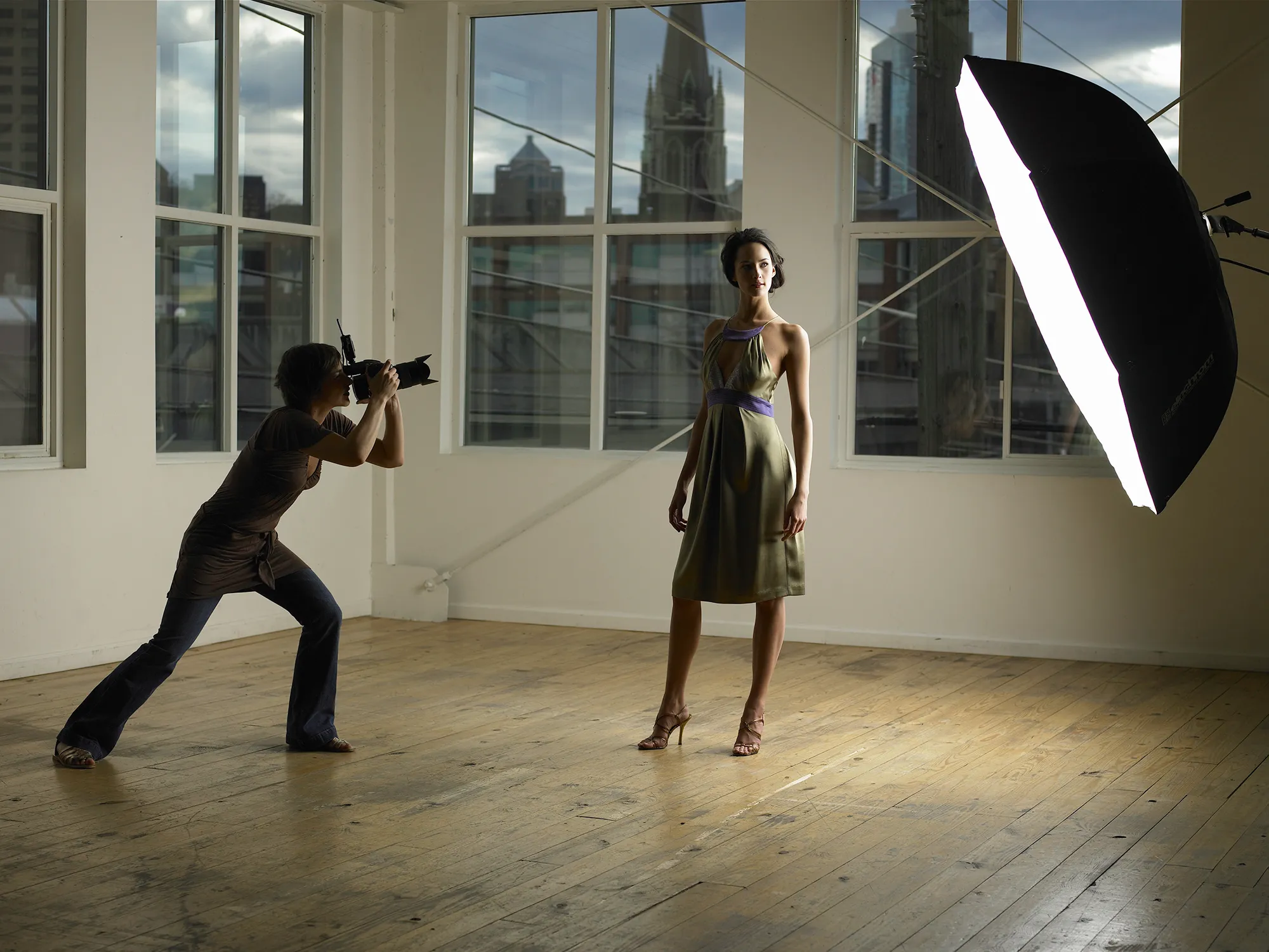 Woman photographing young female model in photo studio, dusk