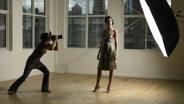 Woman photographing young female model in photo studio, dusk