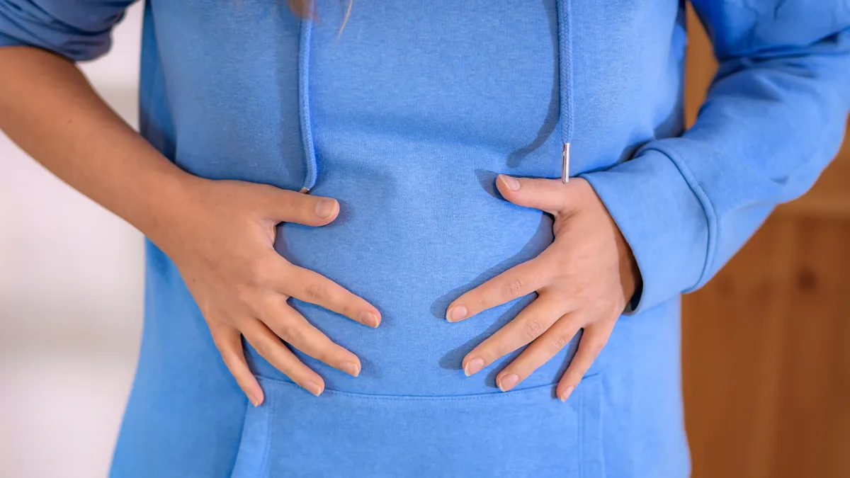 woman having abdominal bloating, overeating, round tummy close up macro