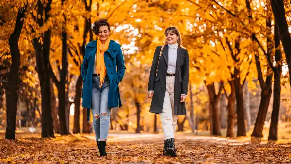 Two beautiful young female friends having a walk in the park during autumn.