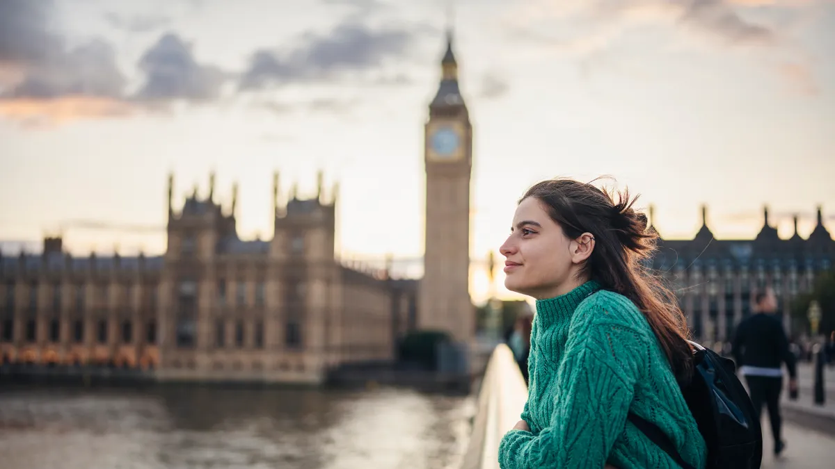 Young female tourist admiring the beauty of city of London on the Westminster bridge next to Big Ben.
