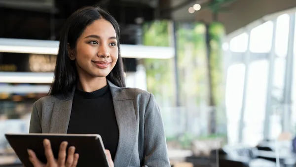 Businesswomen using a tablet while standing and looking away in a financial business office.