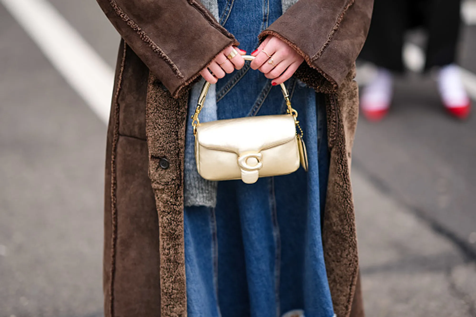 woman holding golden coach bag