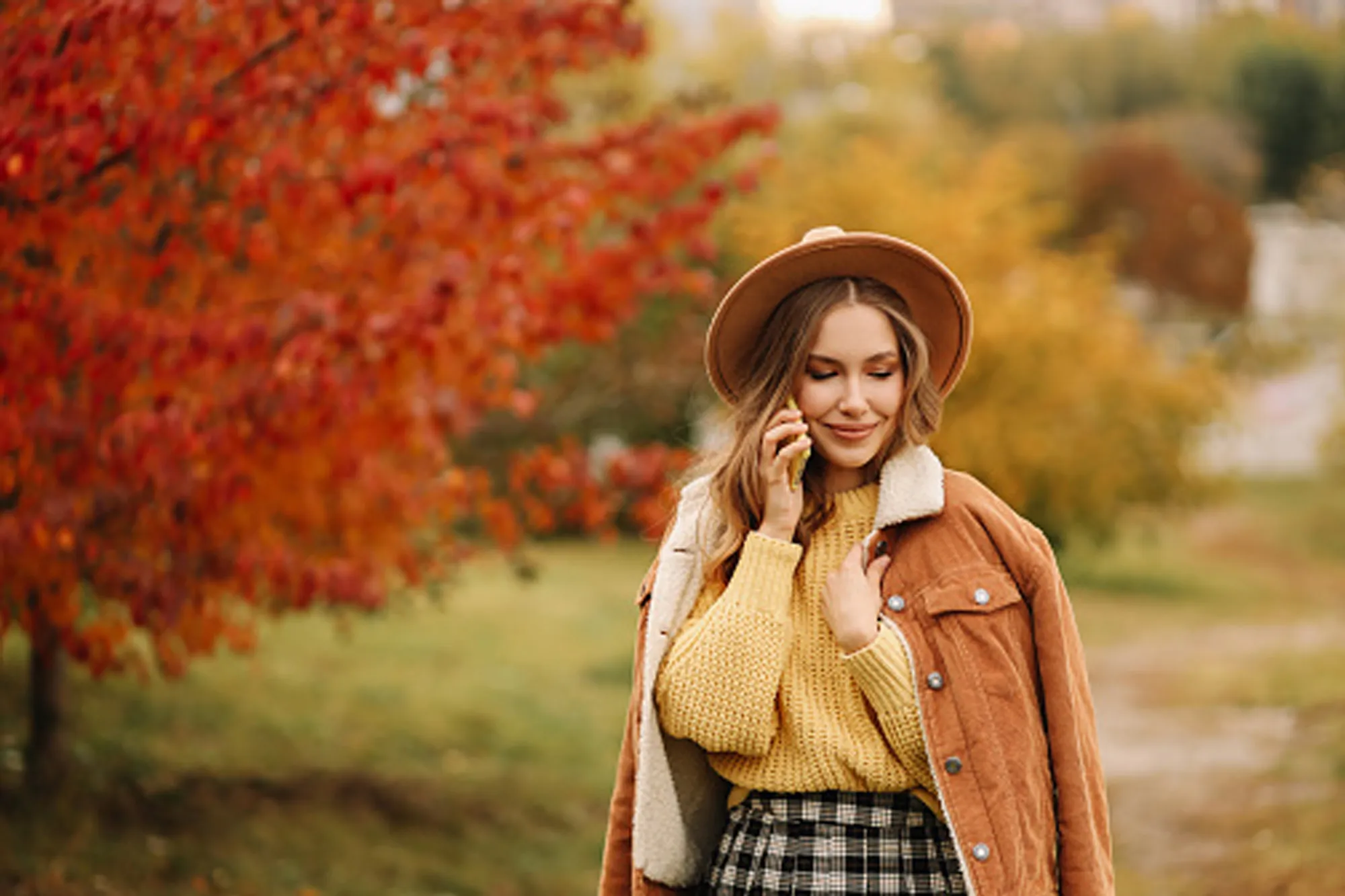 woman wearing jacket, sweater, skirt and hat in autumn setting