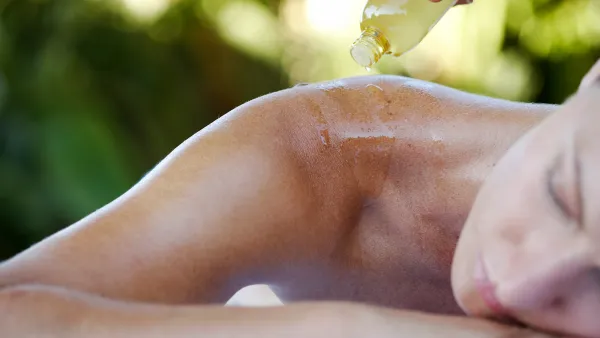 Young woman relaxing, massage oil being poured on back, close-up