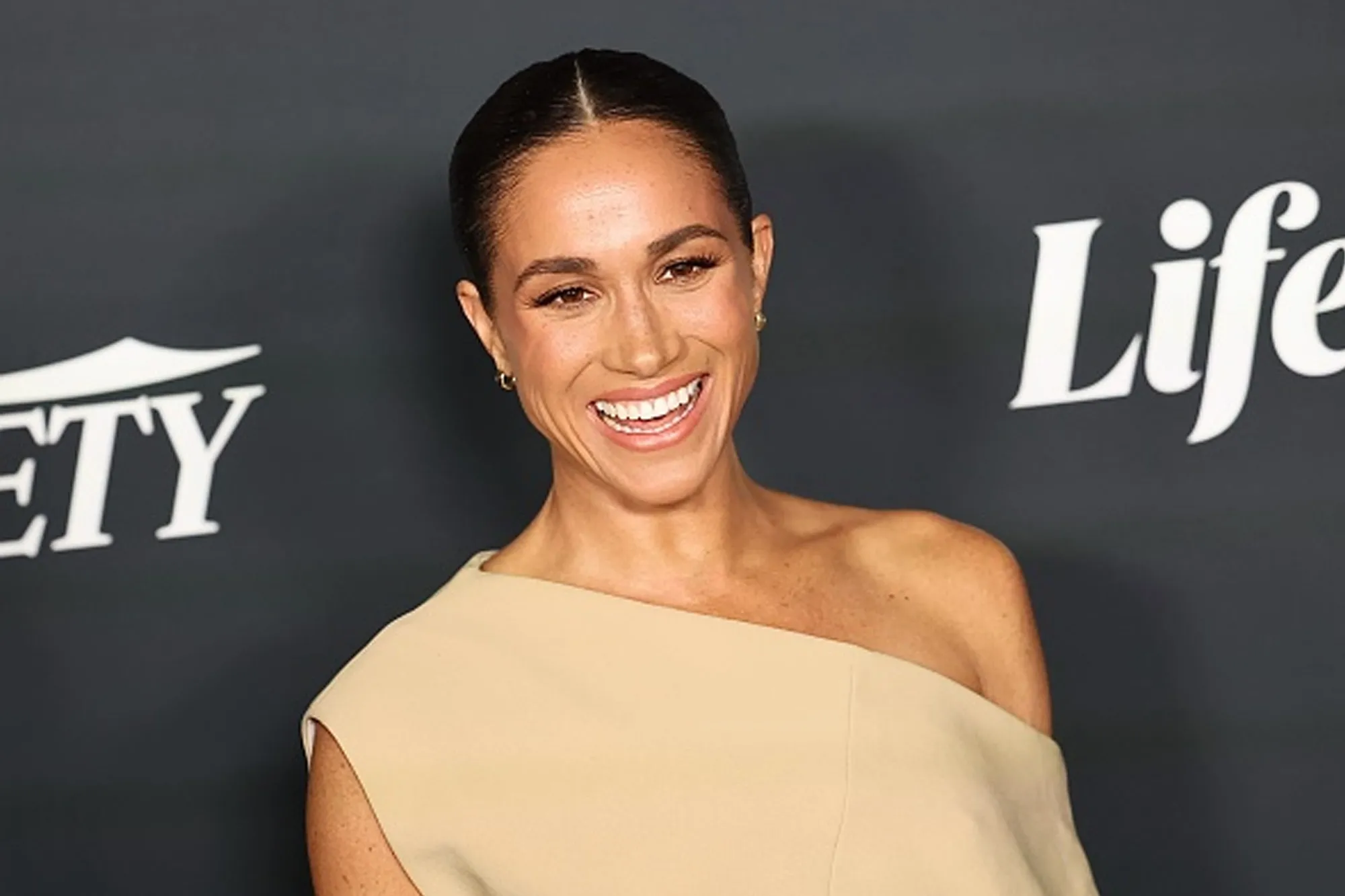 Meghan Markle wearing tan dress on red carpet