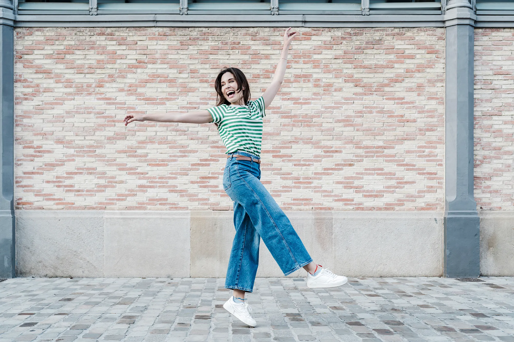 Close-up of pretty woman laughing at camera and walking down a city street.