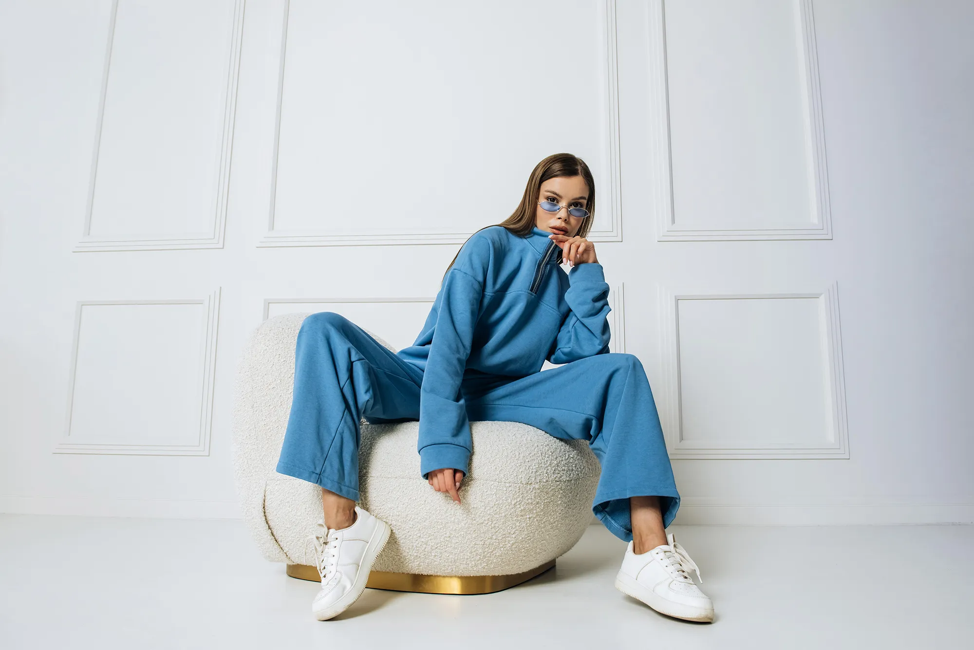 Fashion model woman sitting in a chair posing in a new collection of sportswear.