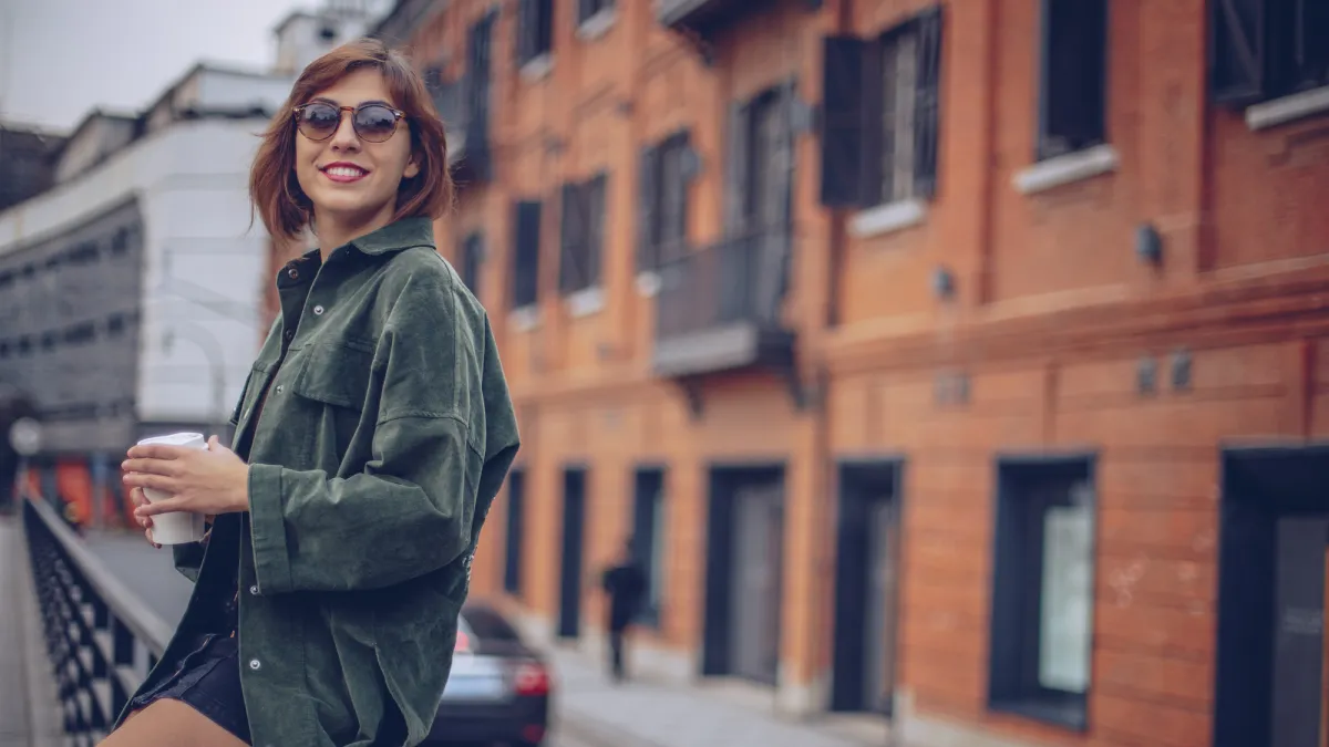 woman sitting on a railing drinking coffee