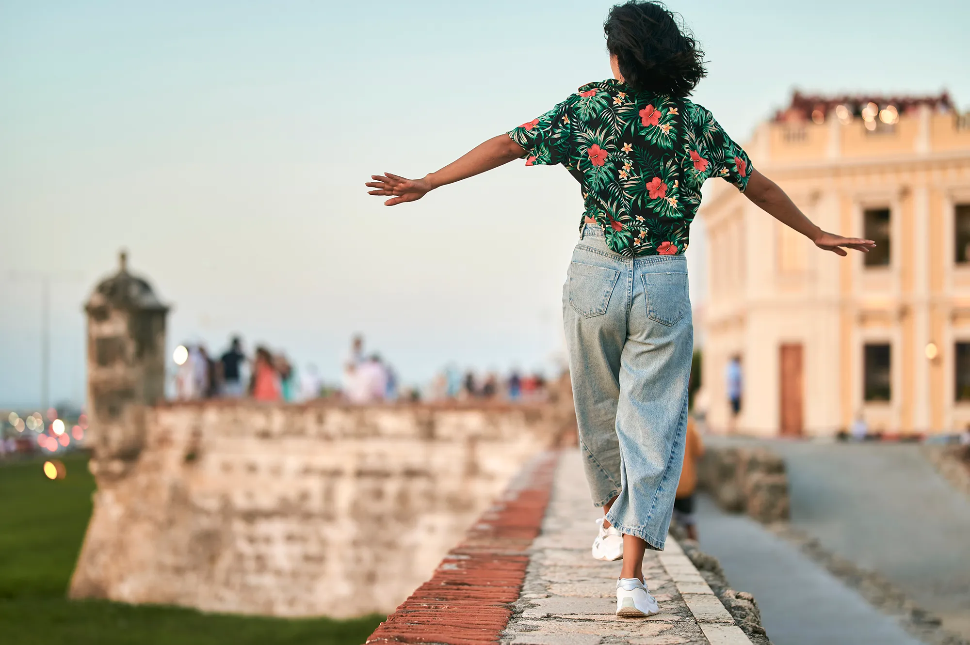Woman walking on wall seen from behind in Cartagena, Colombia