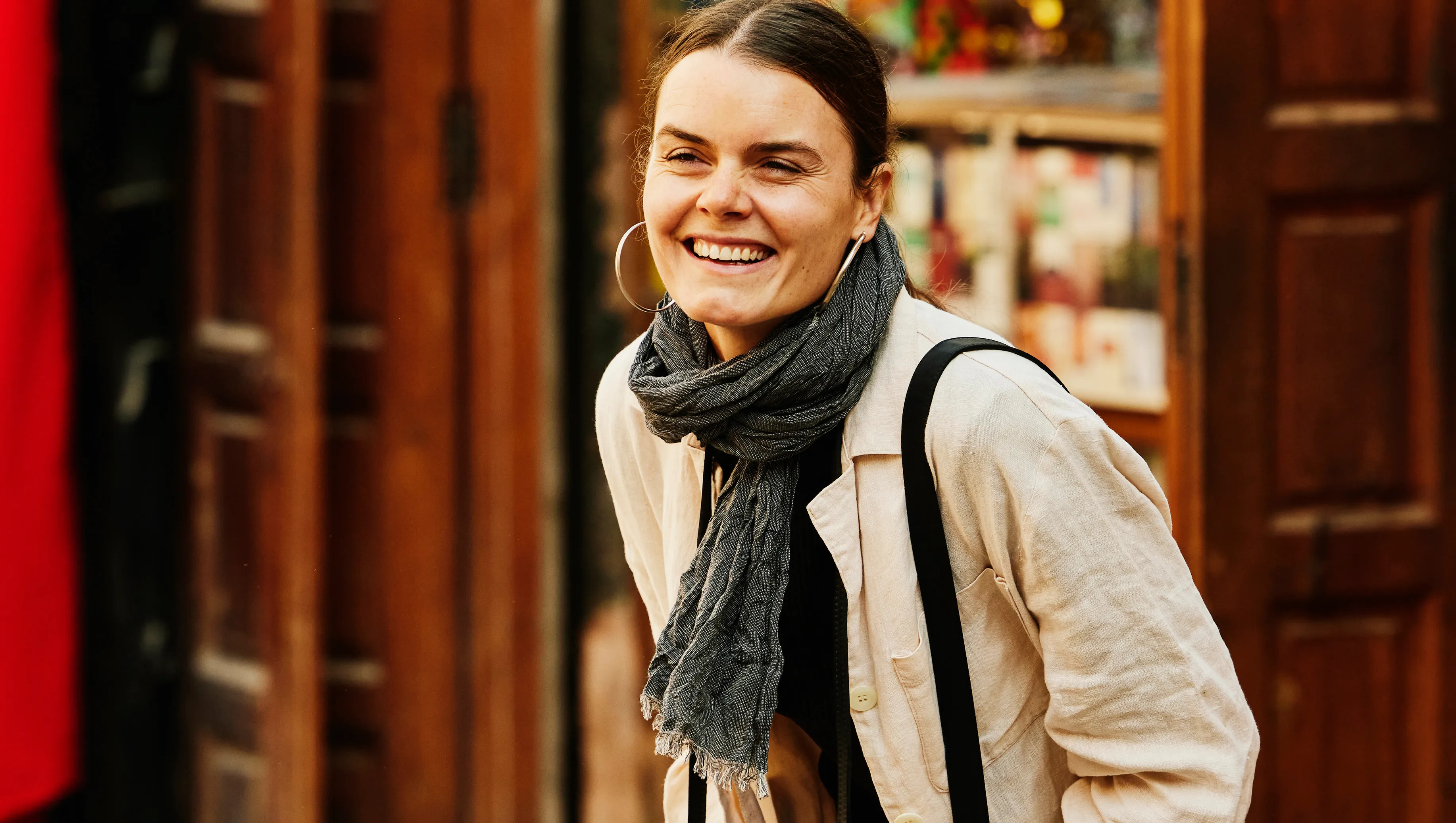 Wide shot of solo female traveler laughing while taking photographs in the medina of Marrakech during vacation in Morocco