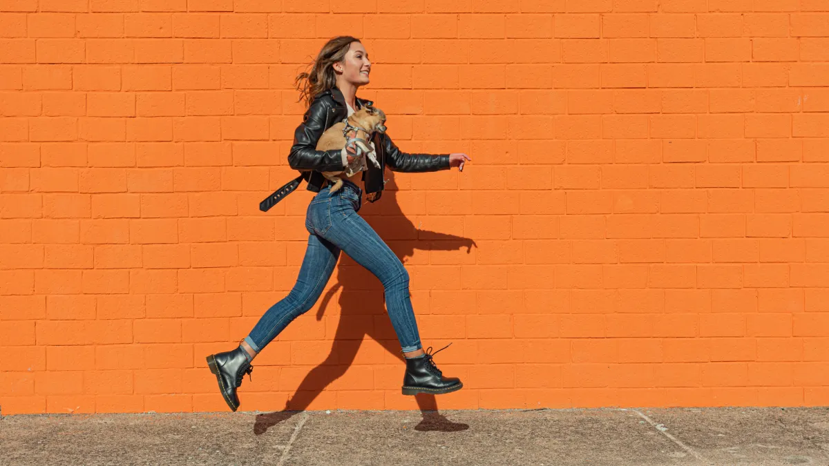 woman wearing leather jacket skipping on a street