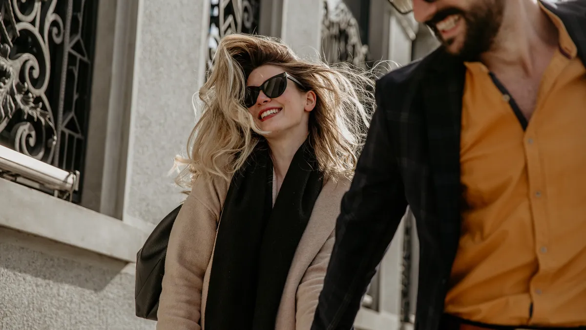 woman in sunglasses walking down a street with a man