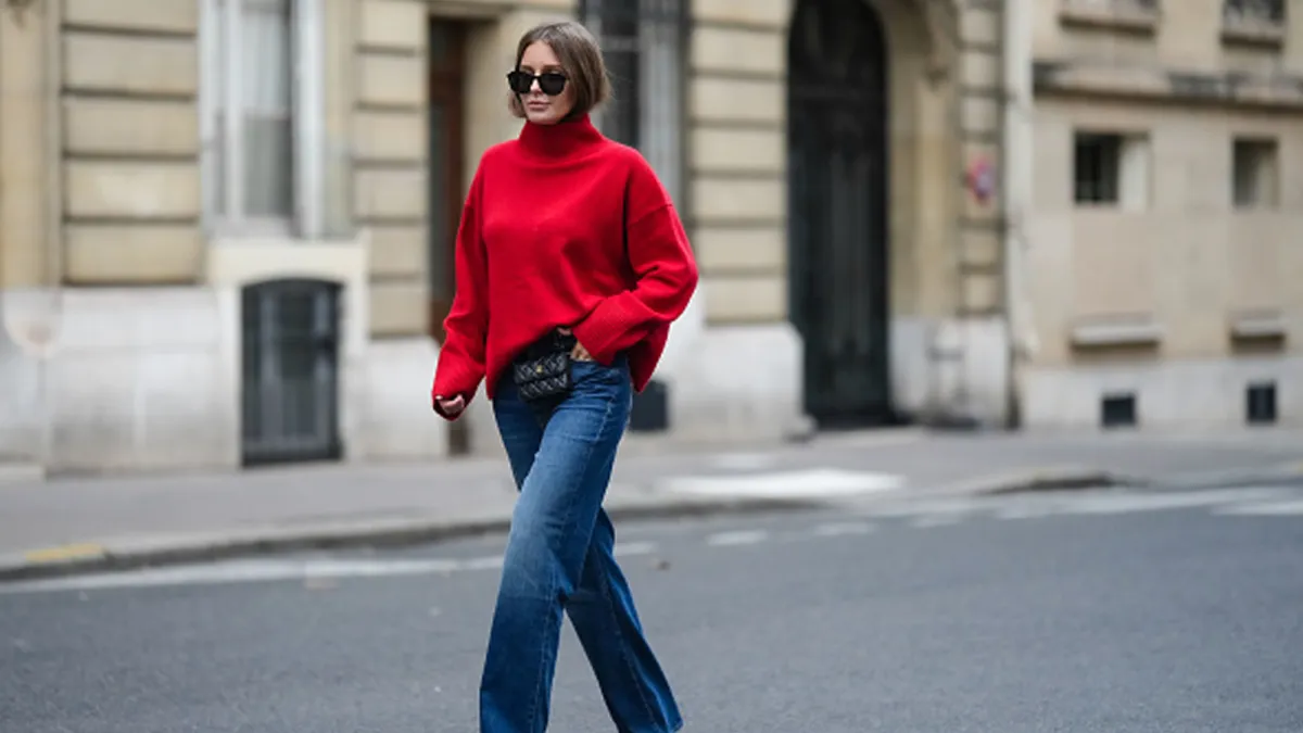 woman wearing loose red sweater and blue jeans