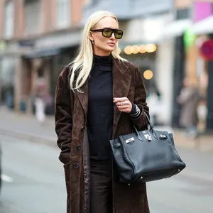 woman wearing brown coat and black bag